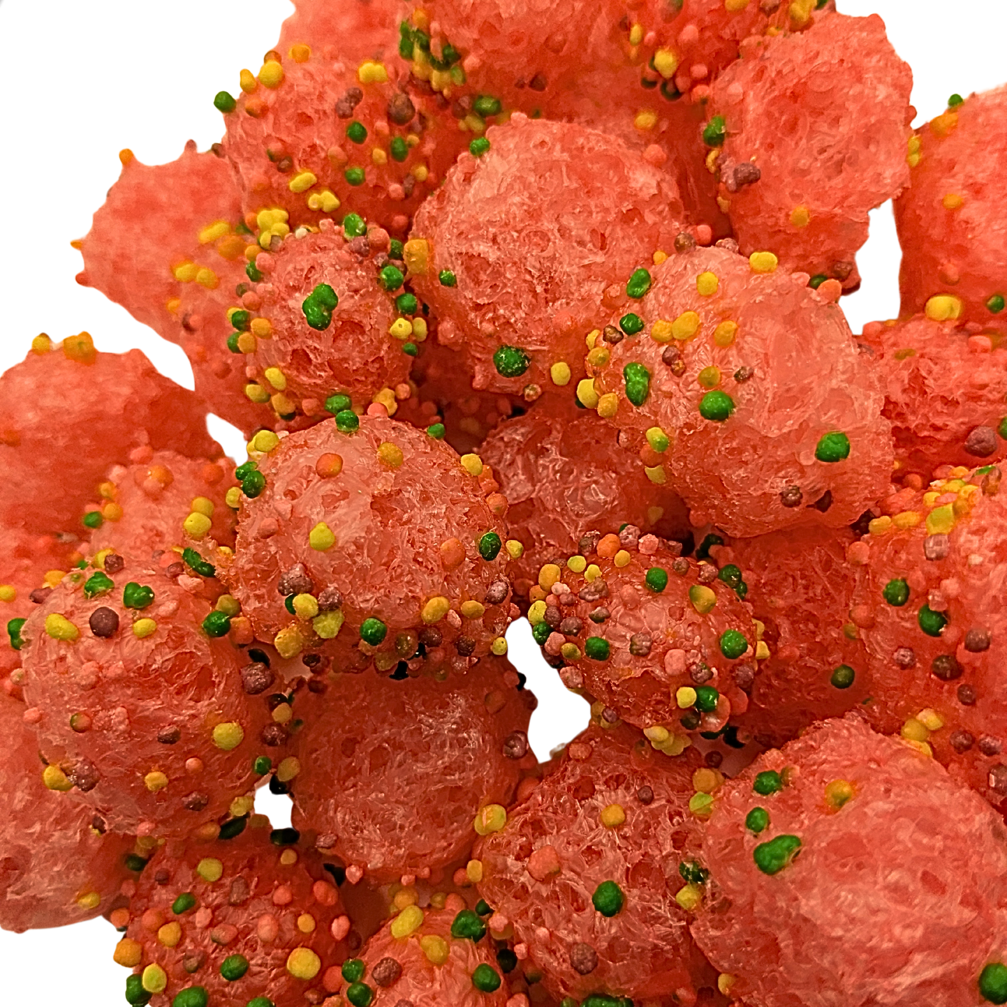 Close-up of bright reddish pink candy sprinkled with green, yellow, and orange sprinkles on a white background.