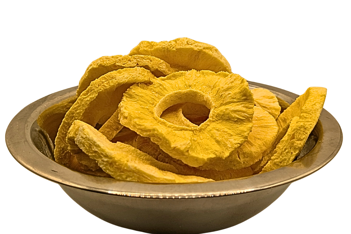 Yellow freeze dried pineapple slices piled in a round metallic bowl on a plain white background.