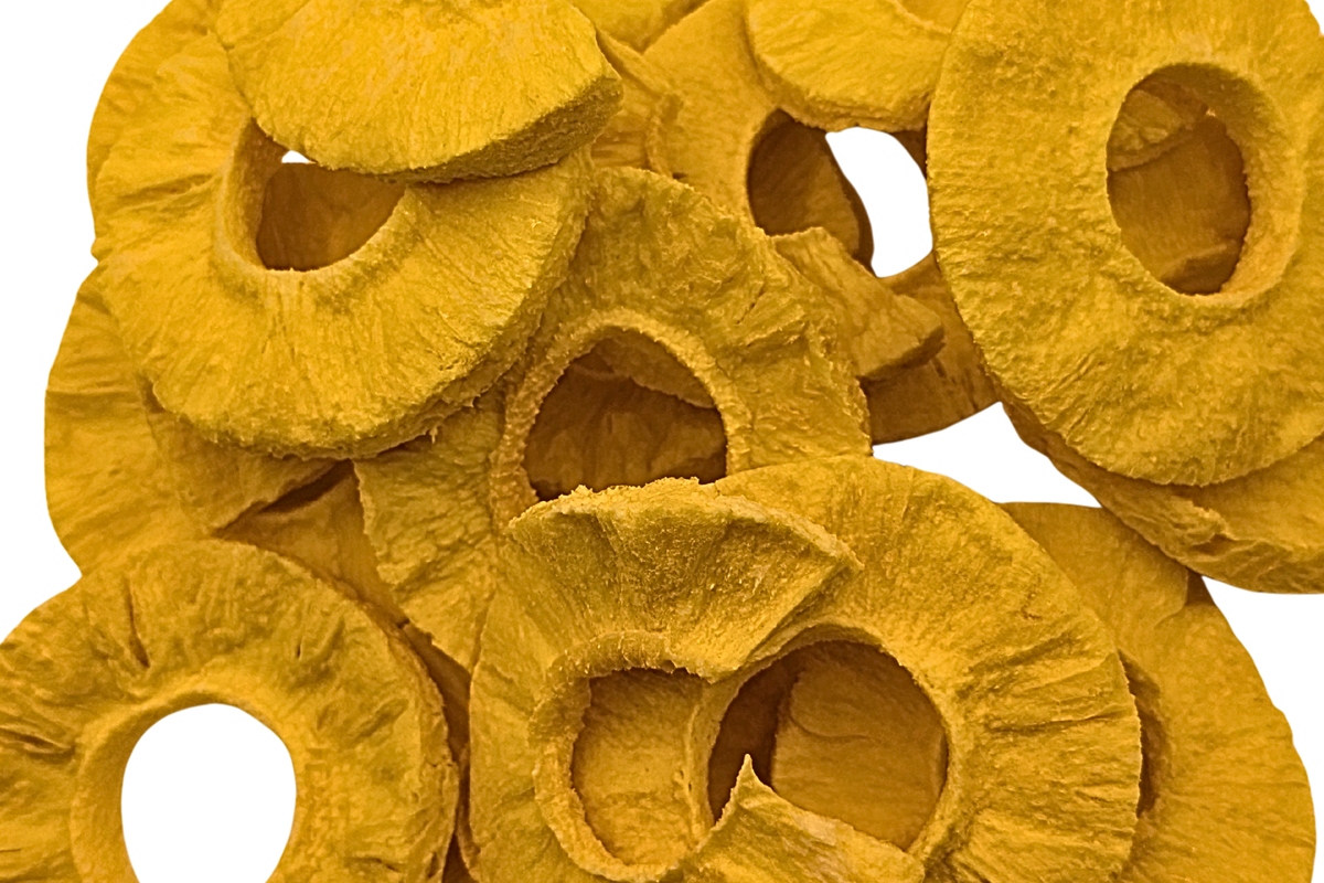 A pile of freeze dried pineapple rings with a textured, fibrous texture in a vibrant golden-yellow color, isolated on a white background.