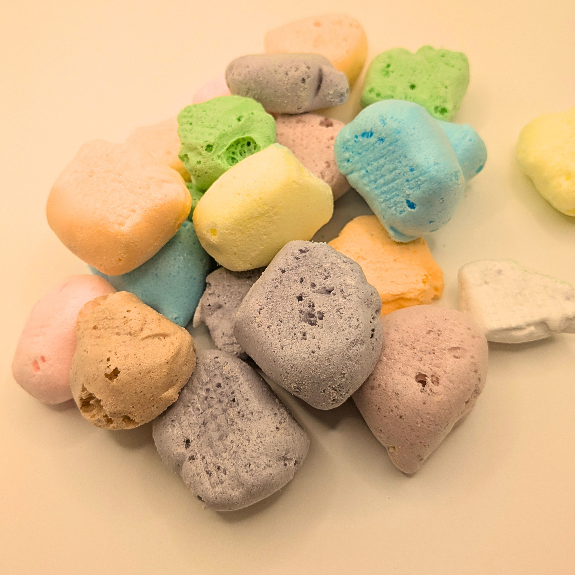 Pile of freeze dried taffy in different flavors on a white background