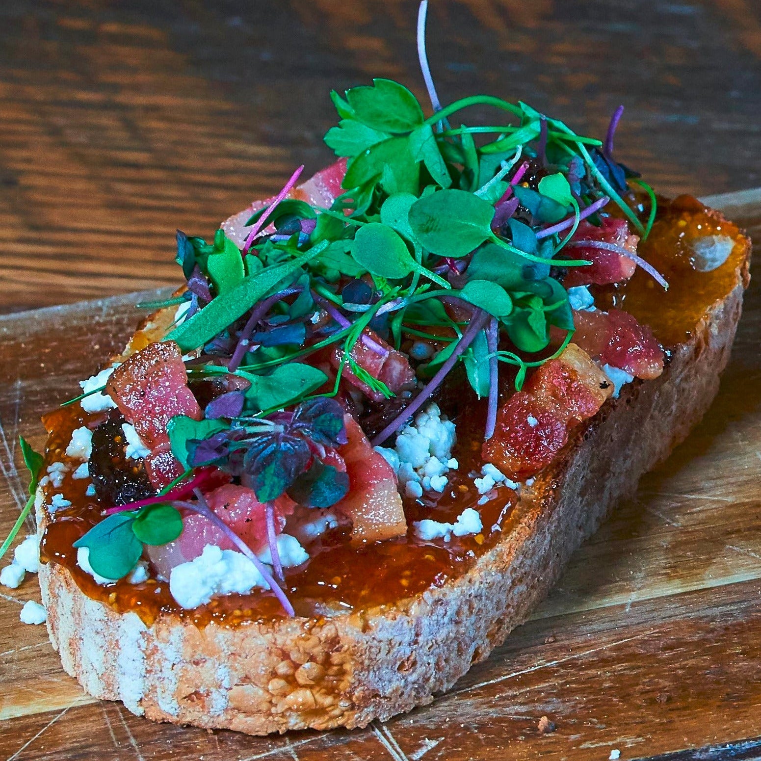 Microgreens being sprinkled into a white bowl against a white background
