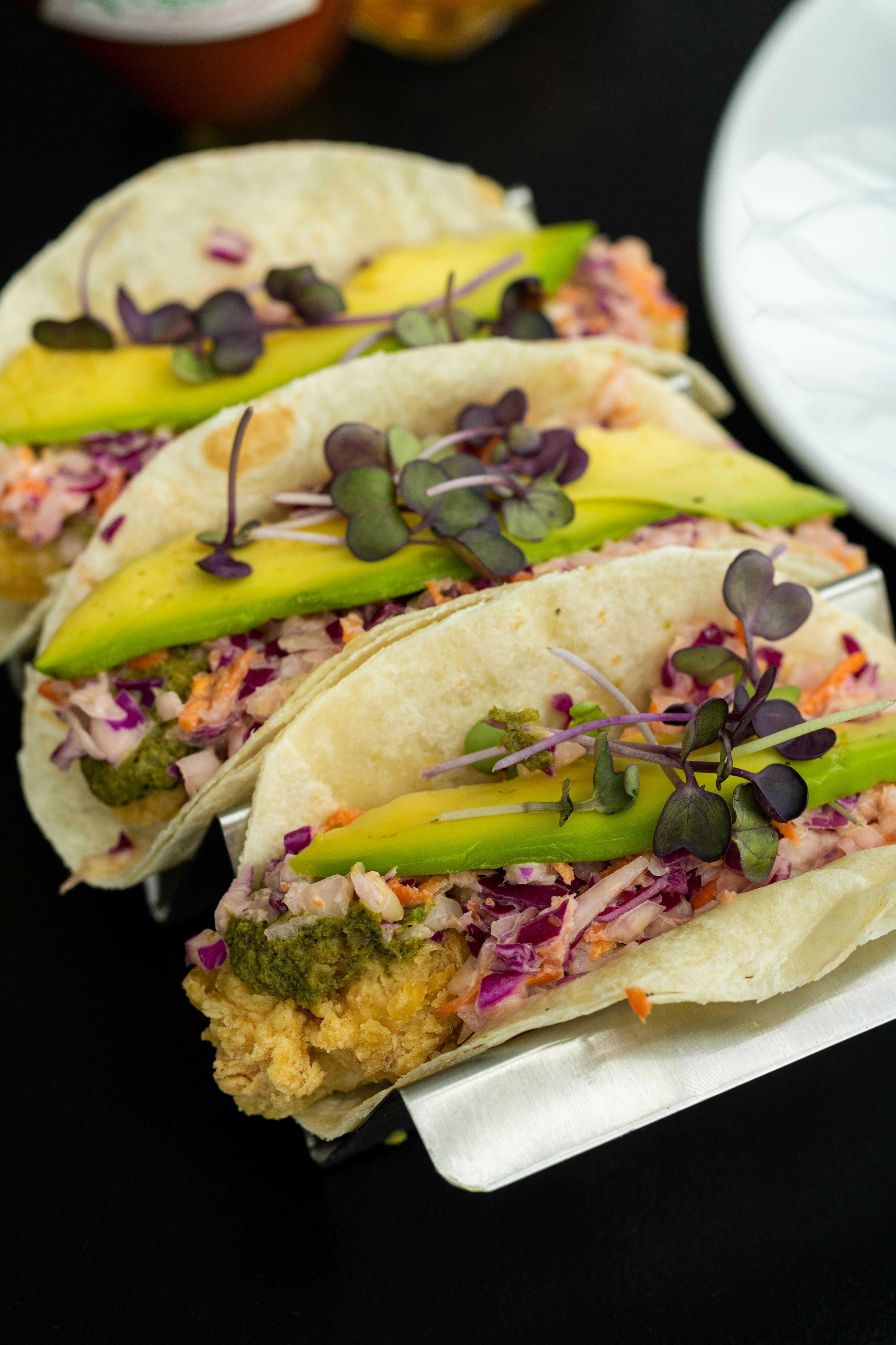 A healthy taco that includes onion, avocado, and microgreens