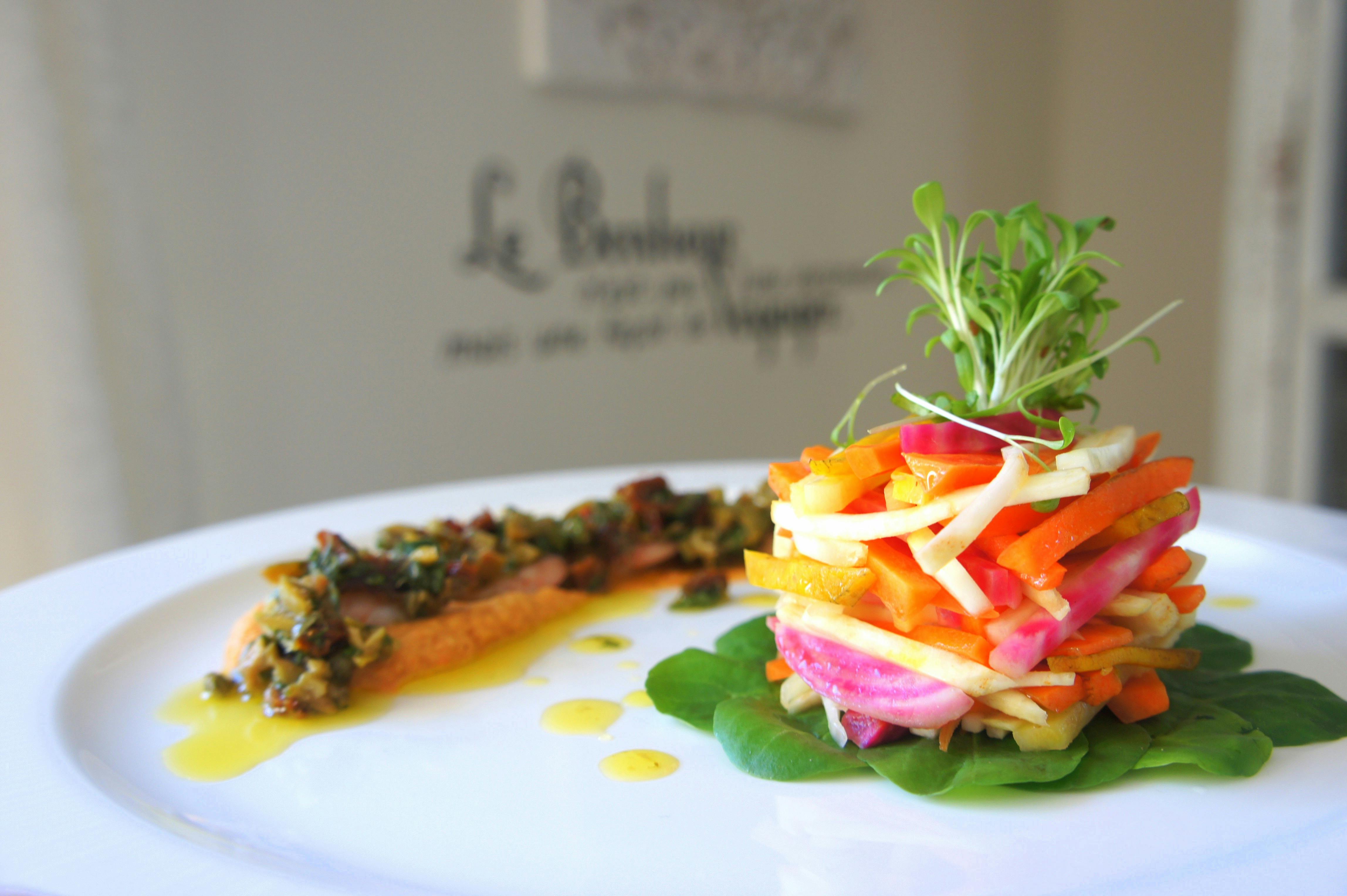A culinary stack of beet, carrot, and microgreens on a white plate
