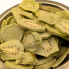 Sliced freeze dried kiwis in a metal bowl on a white background
