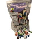 A bag of Freeze Dried Berry Bitz candy with several loose multicolored candies spilled in front on a white background.