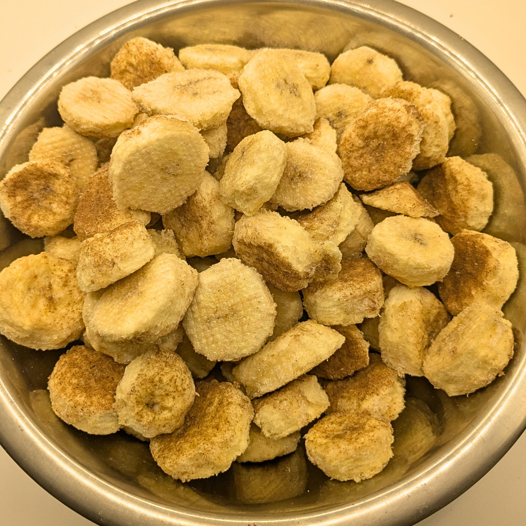 Freeze dried honey cinnamon bananas in a metal bowl on a white background