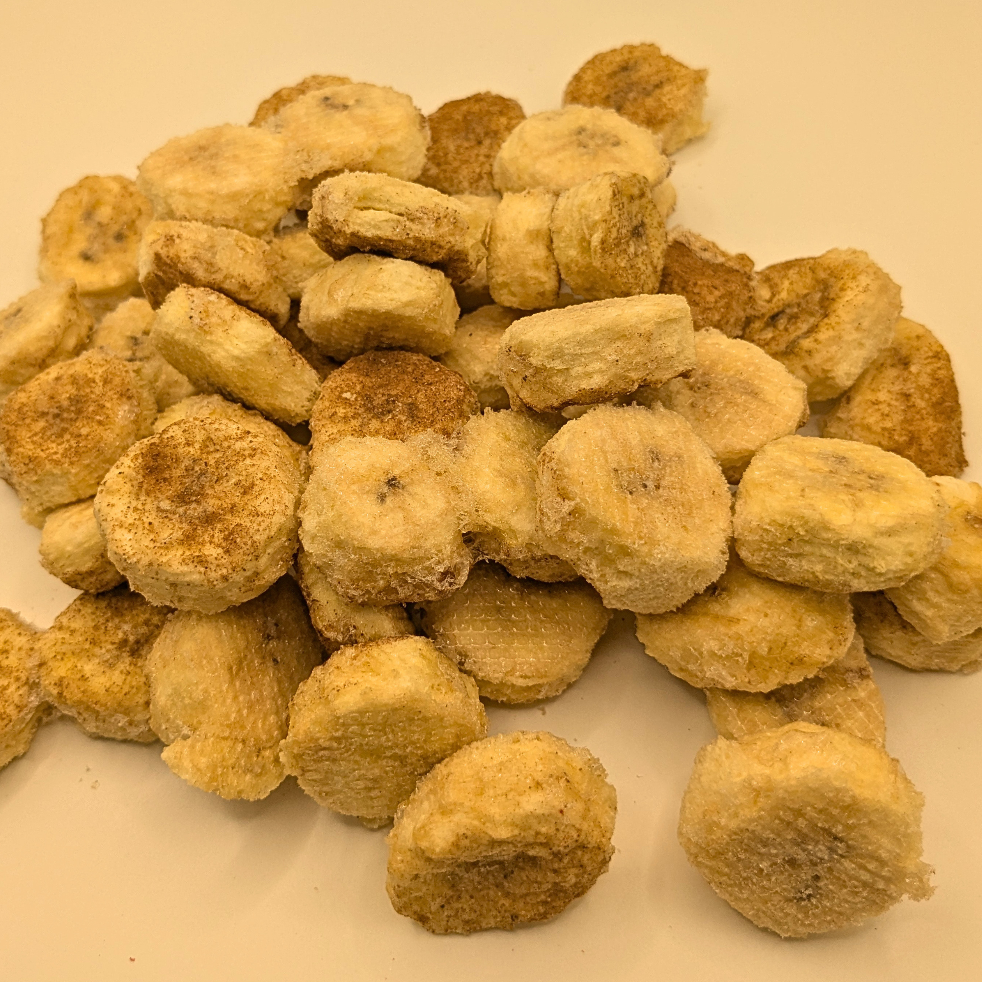 A pile of freeze dried honey cinnamon bananas on a white bacckground