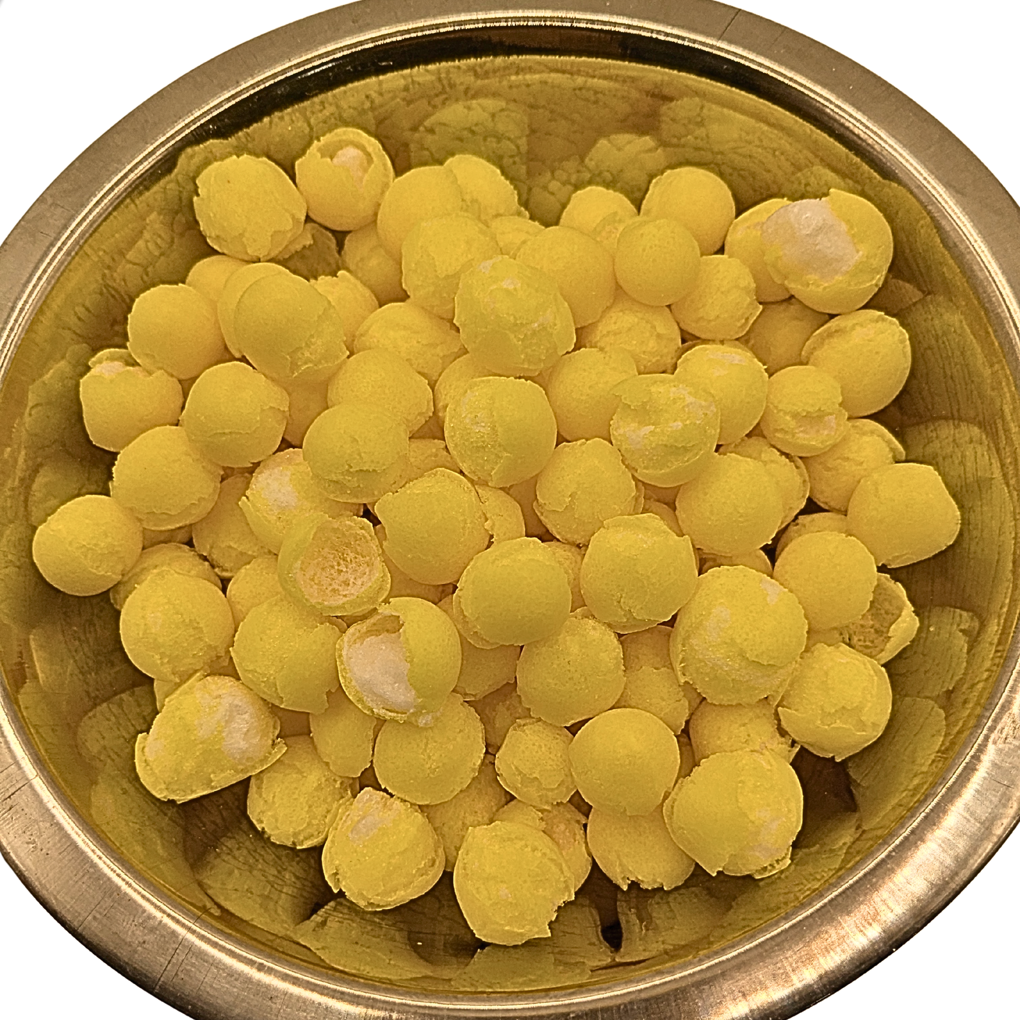 Yellow spherical freeze dried lemon candy piled inside a round metallic gold bowl, photographed from above on a white background.