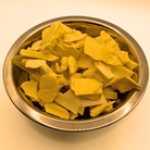A metal bowl full of freeze dried mango slices on a white background