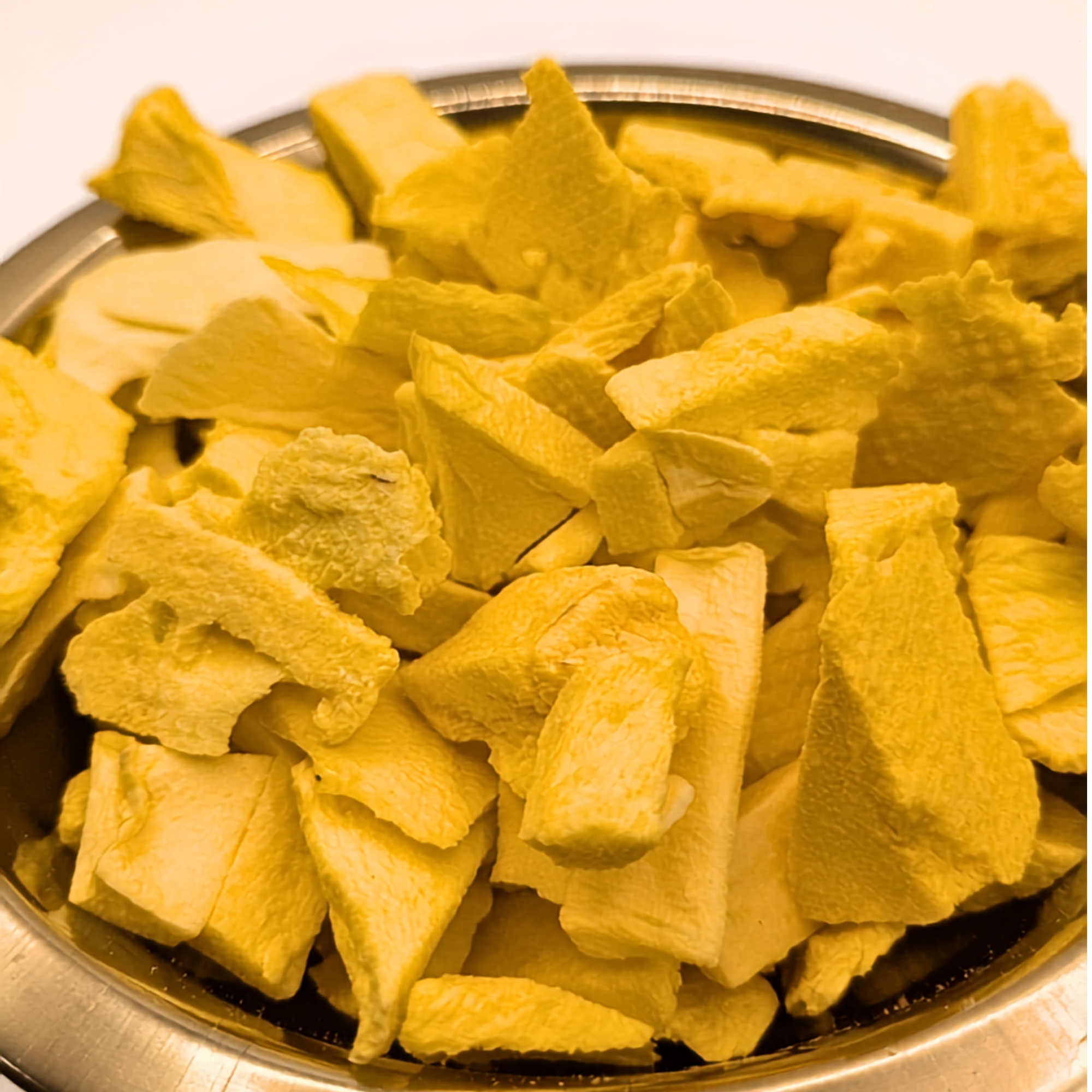 A closeup of a metal bowl full of freeze dried mango slices