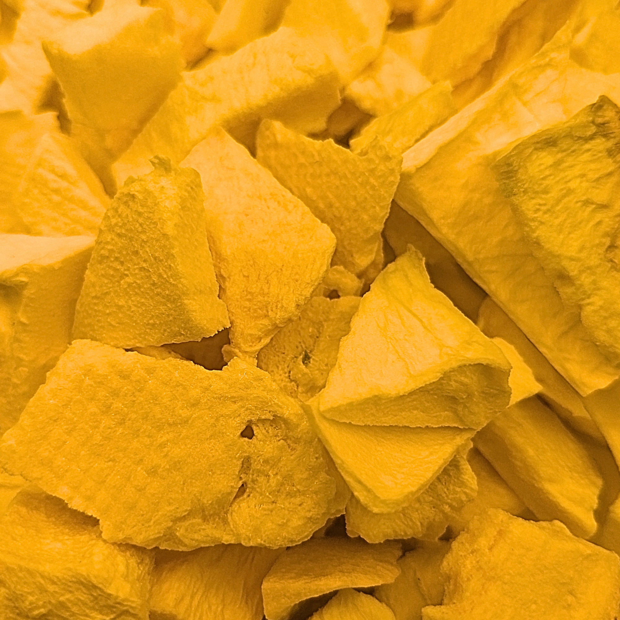 A close-up of freeze dried mango slices, which are a yellowish orange
