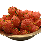 A close-up of pink, crunchy candy sprinkled with colorful round sprinkles, served in a metal bowl against a white background.