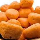 A close-up pile of orange irregularly shaped freeze dried orange taffy on a white background.