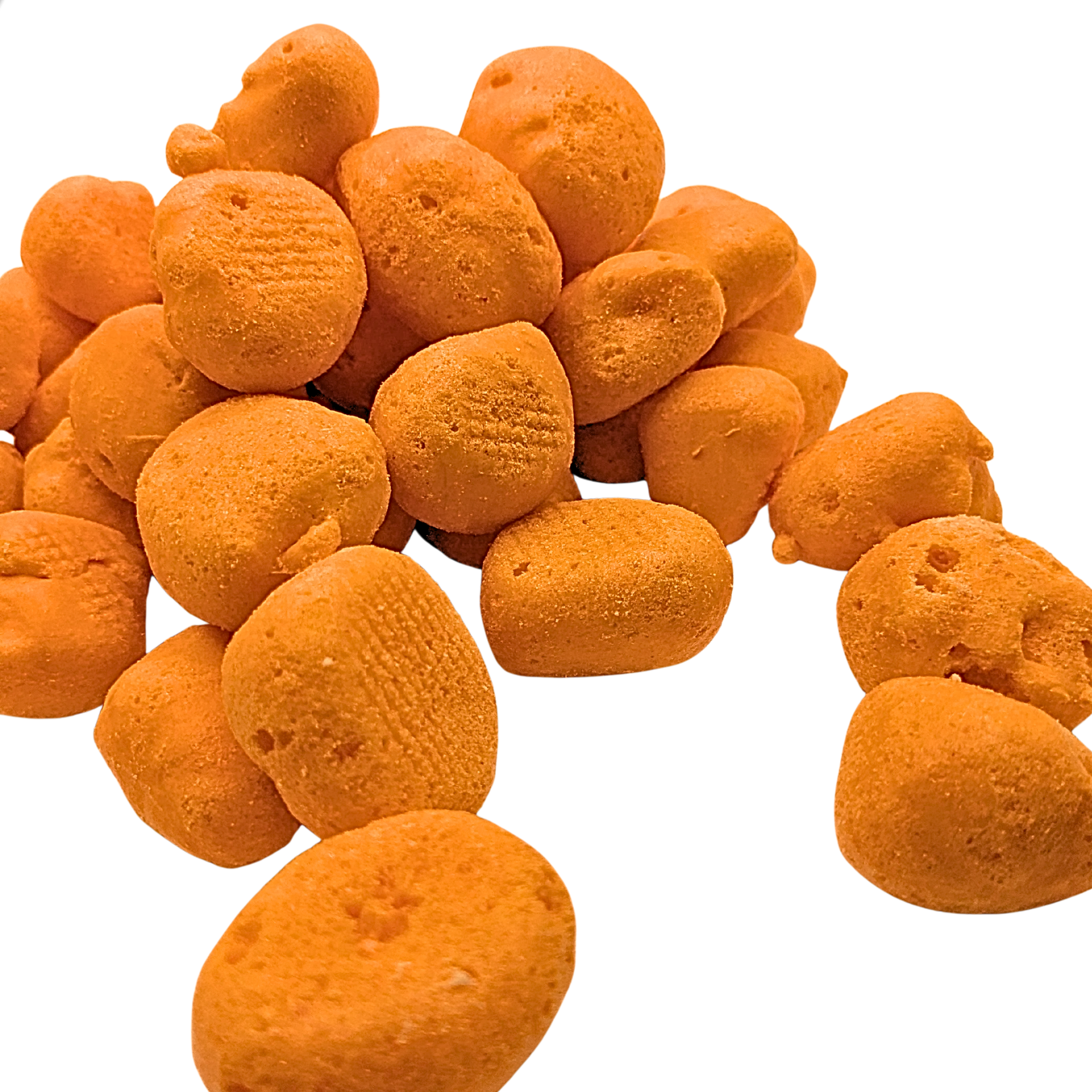 A pile of small, textured orange freeze dried taffy on a solid white background.