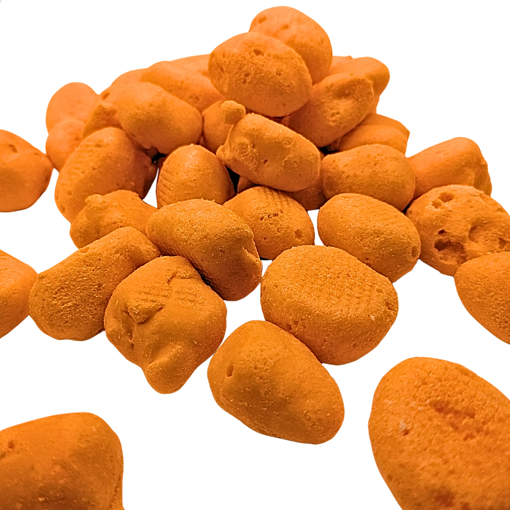A pile of small, irregularly shaped orange freeze dried taffy isolated on a white backgroud