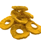 A pile of freeze dried pineapple slices in a bright yellow-orange color, arranged on a plain white background.