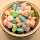 Metal bowl full of freeze dried taffy in different flavors on a white background