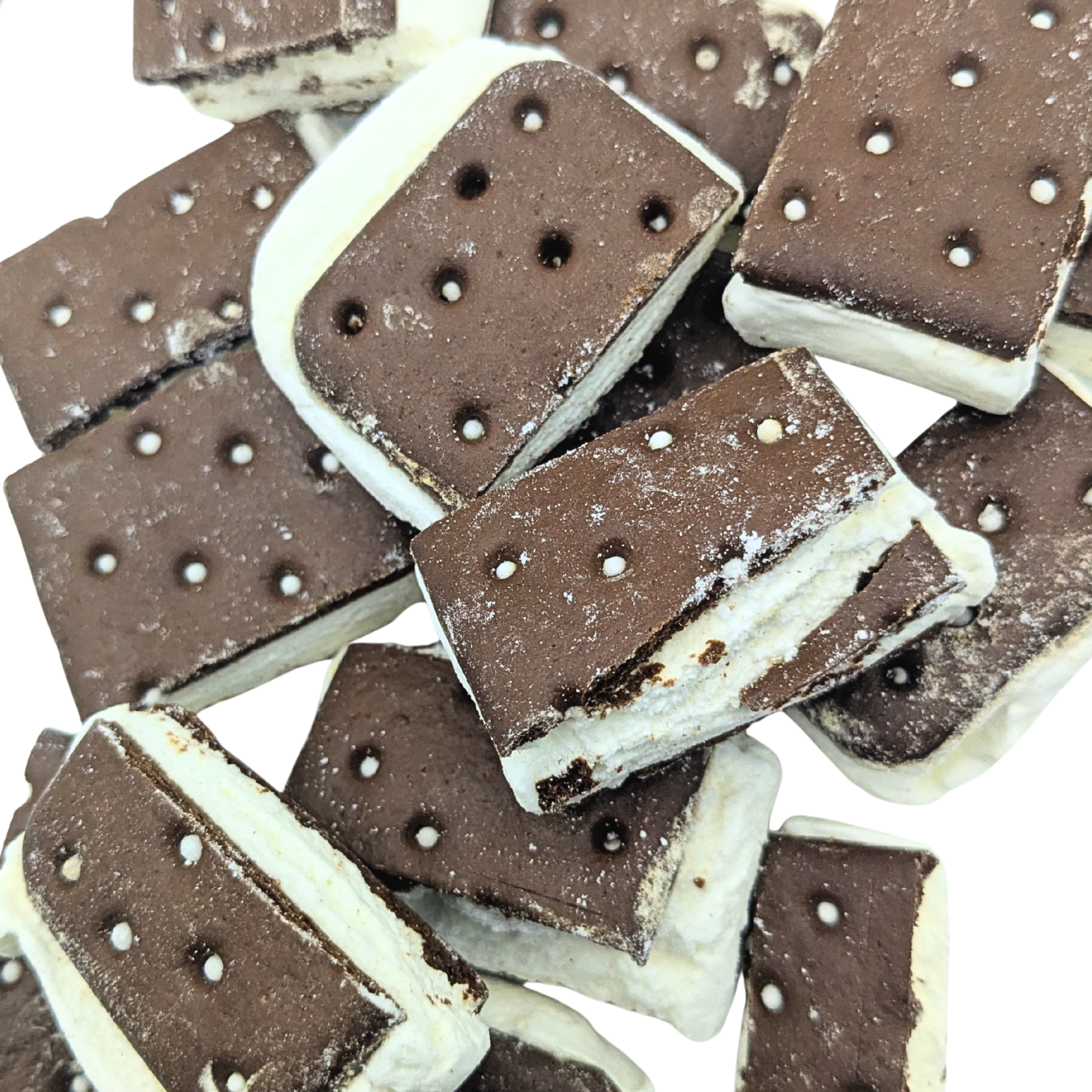 A pile of freeze dried chocolate ice cream sandwiches with chocolate cookies and vanilla filling, photographed close-up on a white background.